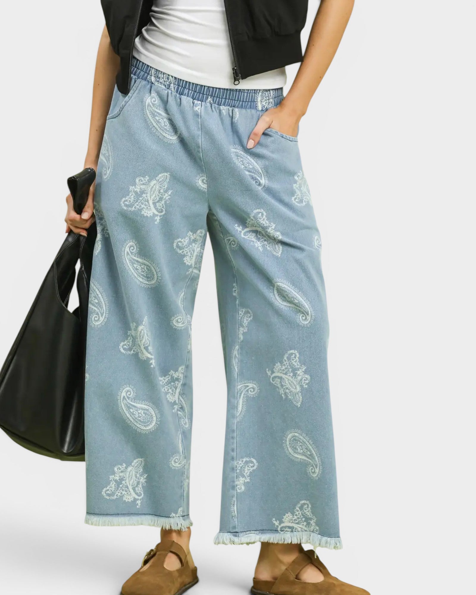 Light blue denim pants with paisley pattern worn by a person on a white background