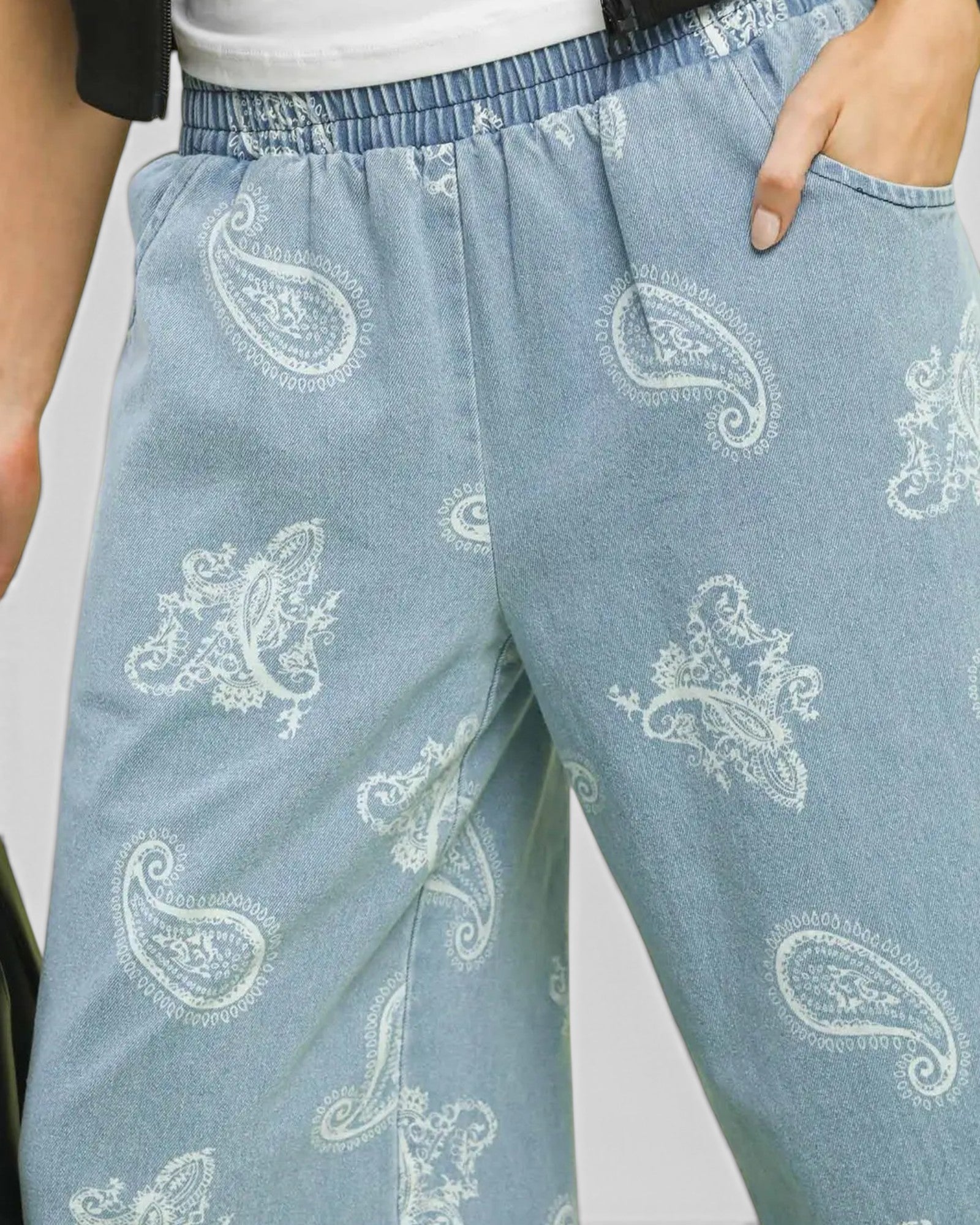 Light blue denim pants with white paisley patterns worn by a person.