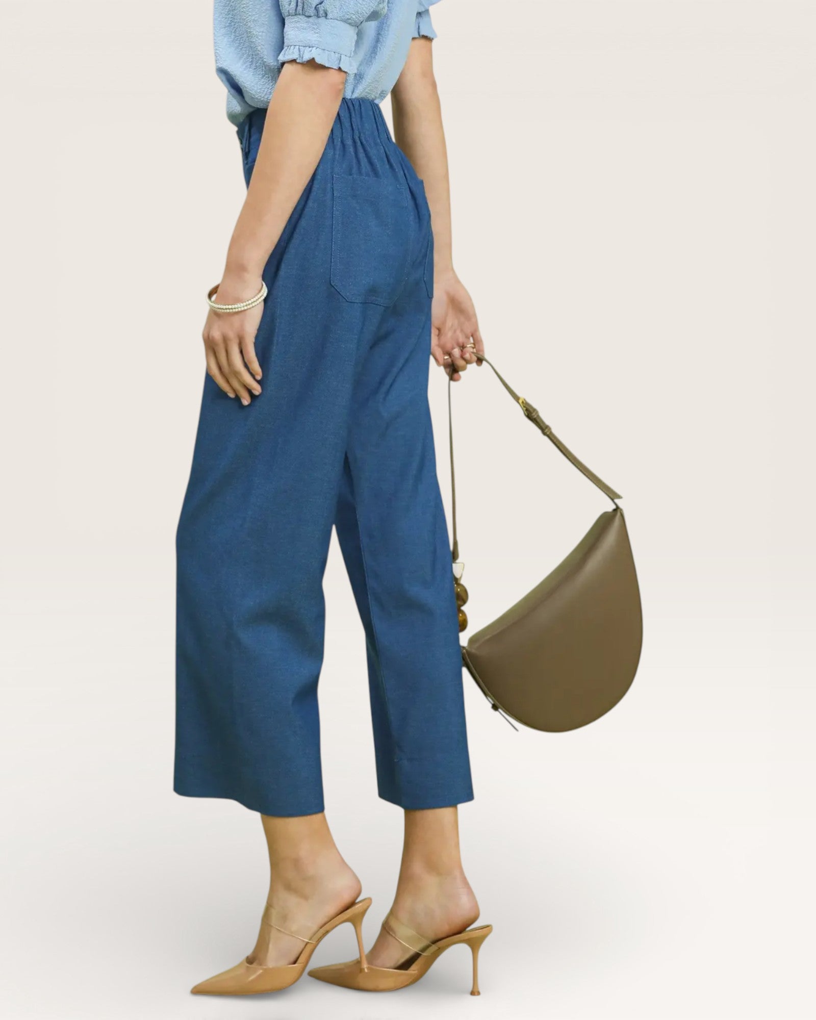 Person wearing blue pants and holding a green bag on a white background
