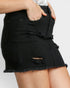 Black denim skirt with frayed edges worn by a person on a plain background