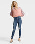 Woman wearing a pink blouse with ruffled sleeves and blue jeans on a white background