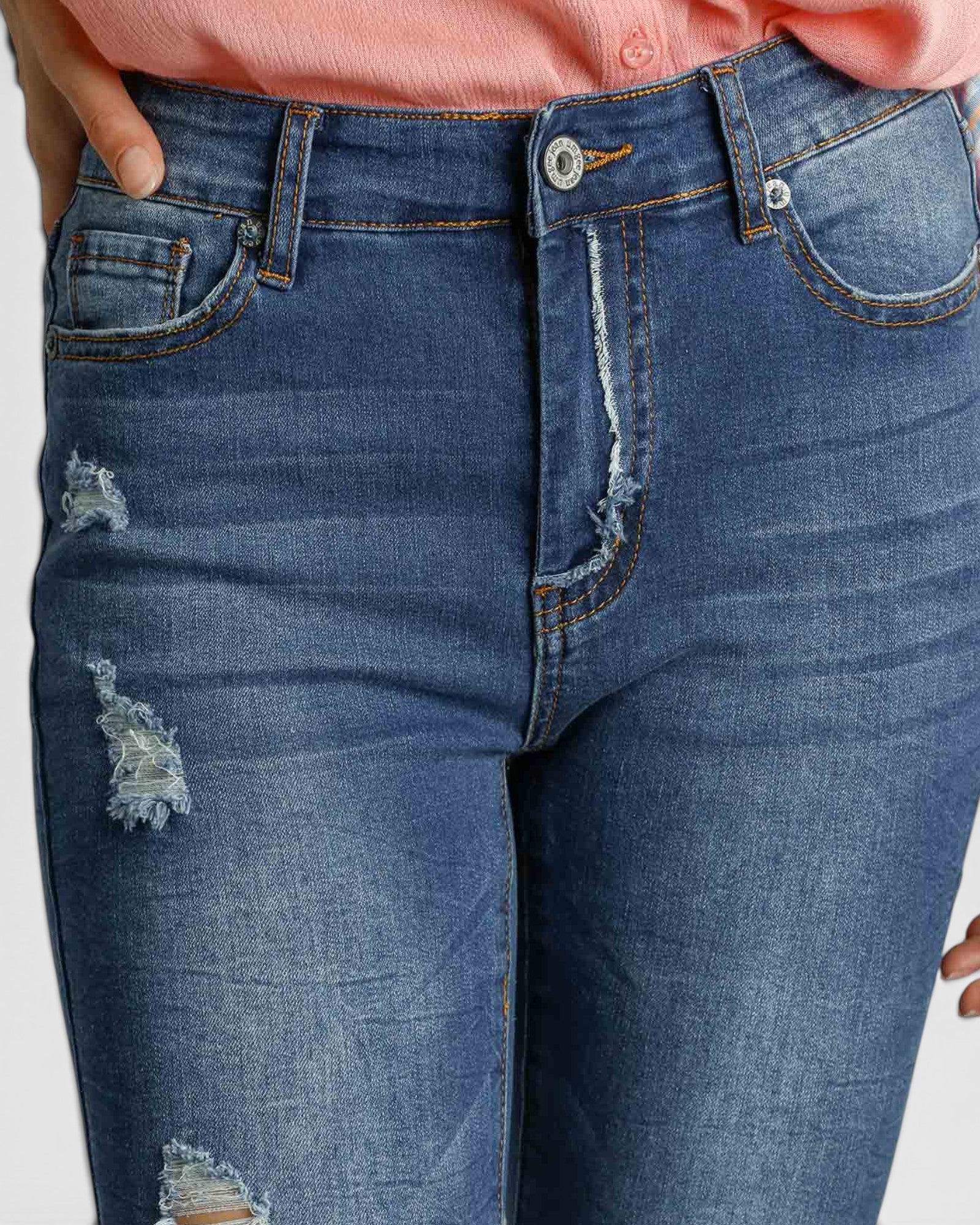 Close-up of blue jeans with distressed details on a plain background
