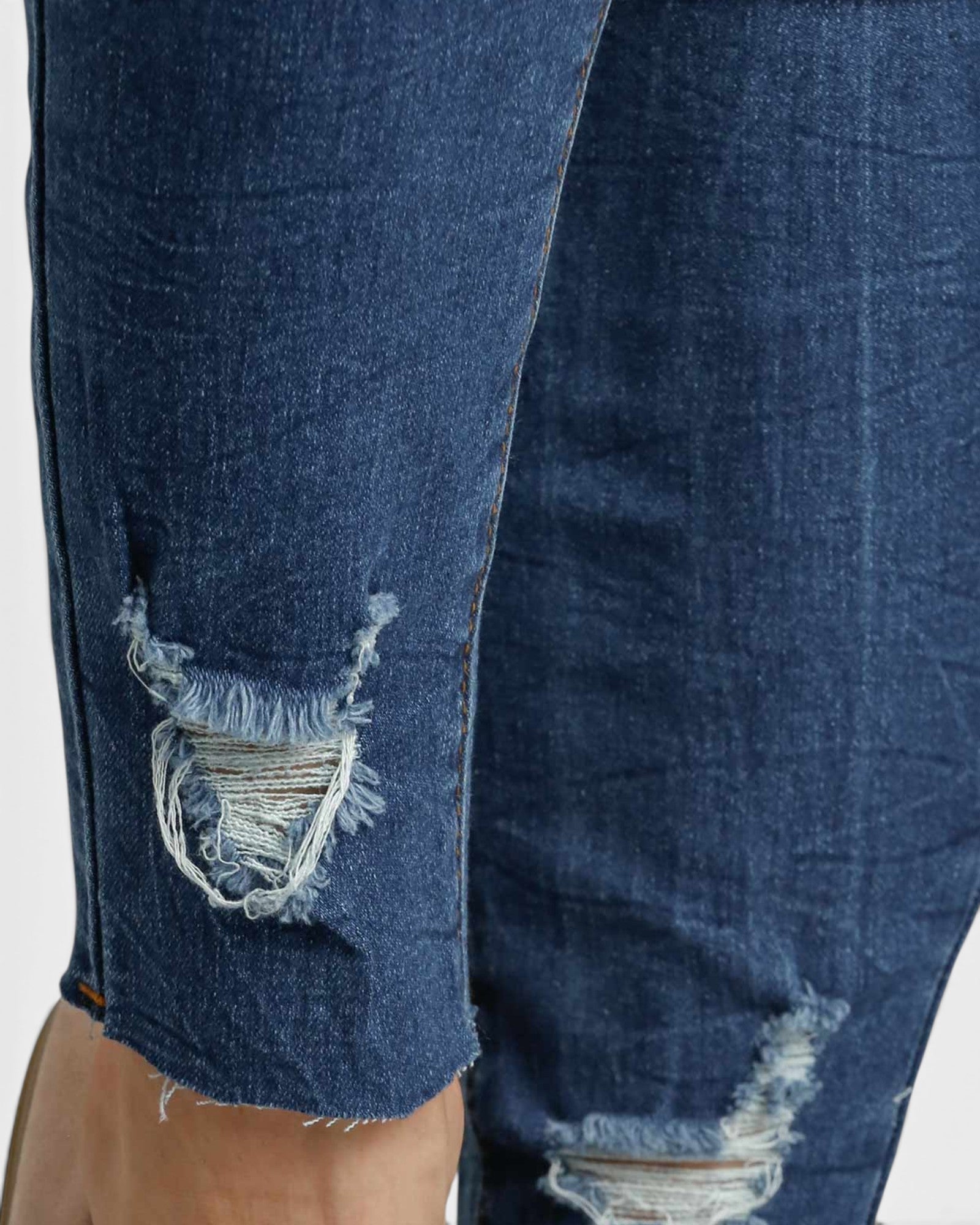 Close-up of blue jeans with frayed edges on a white background