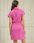 Woman wearing a pink dress against a beige paneled wall