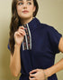 Woman wearing a navy blue top with floral embroidery on a beige background