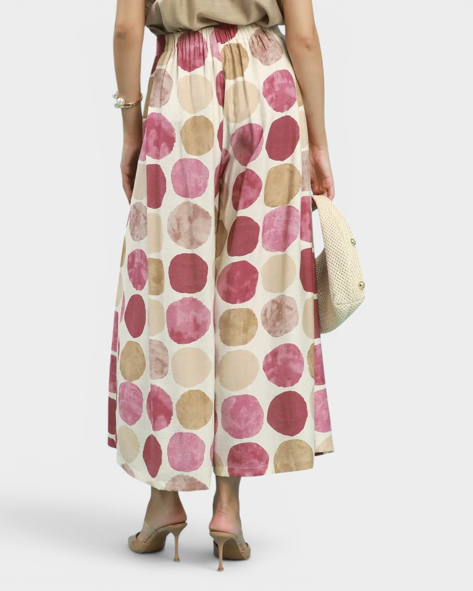 Woman wearing pants with pink and beige polka dots on a white background
