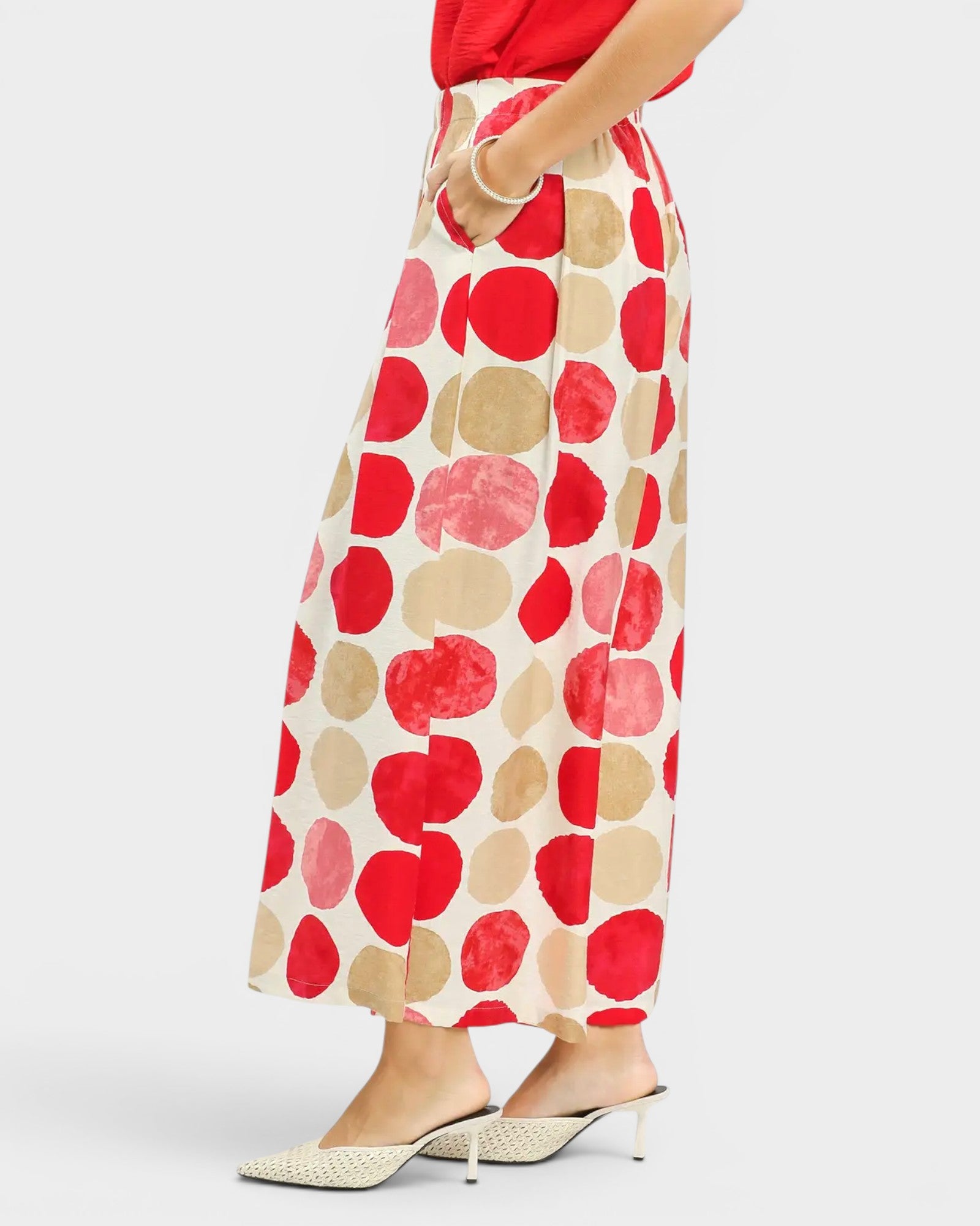 Person wearing a red and beige polka dot skirt on a white background