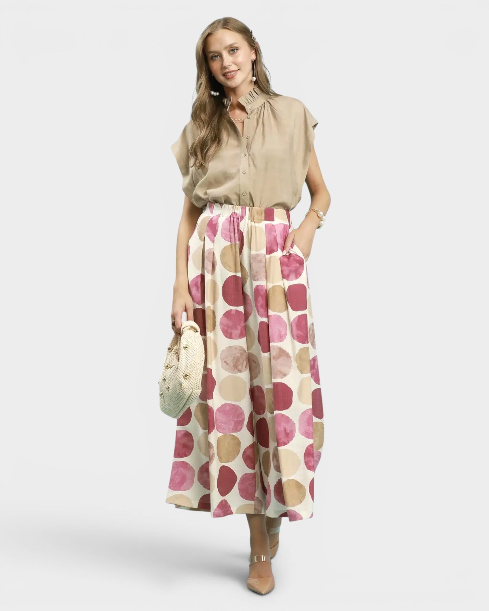 Woman wearing a beige blouse and patterned pants on a white background