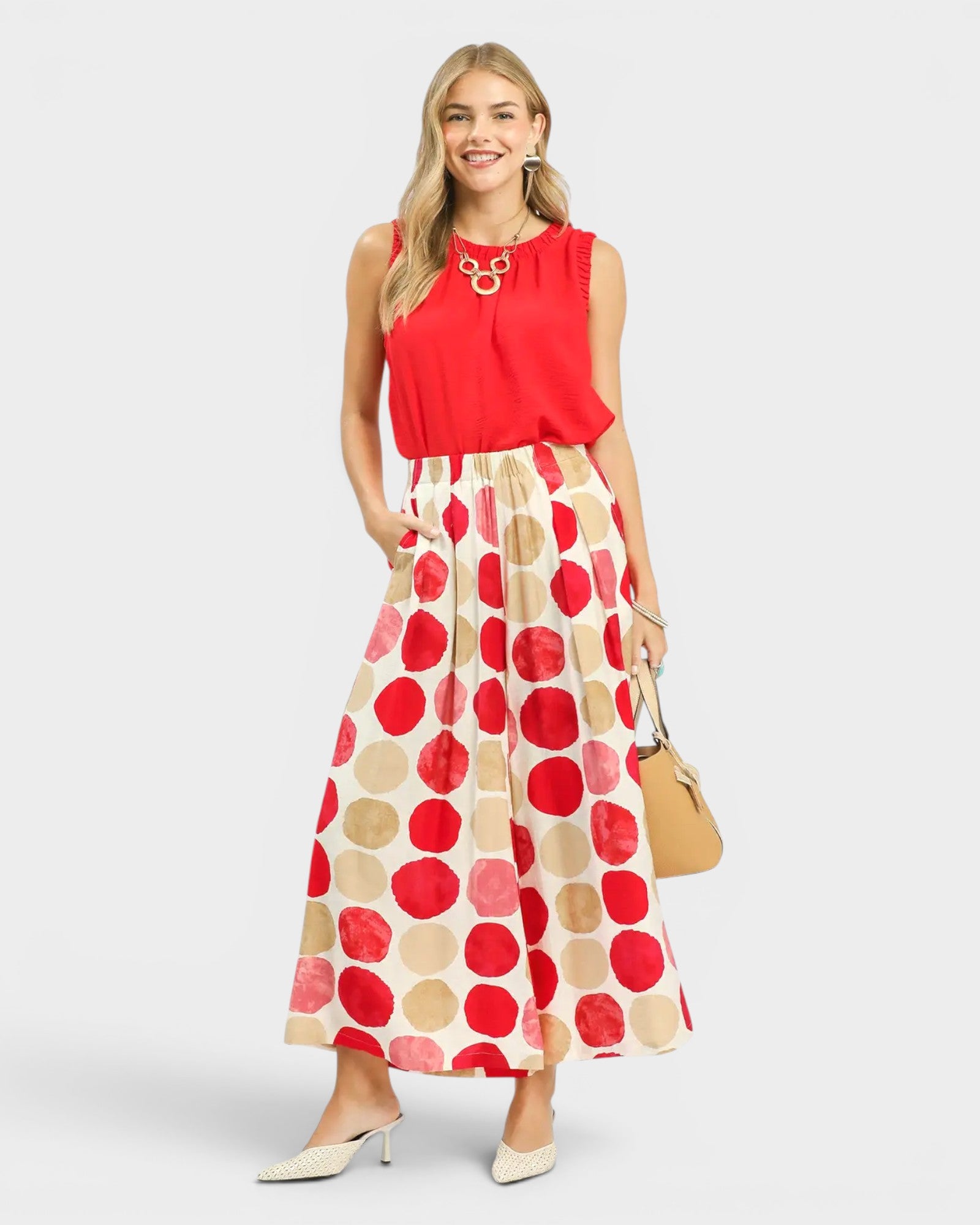 Woman wearing a red sleeveless top and a long polka dot skirt on a white background