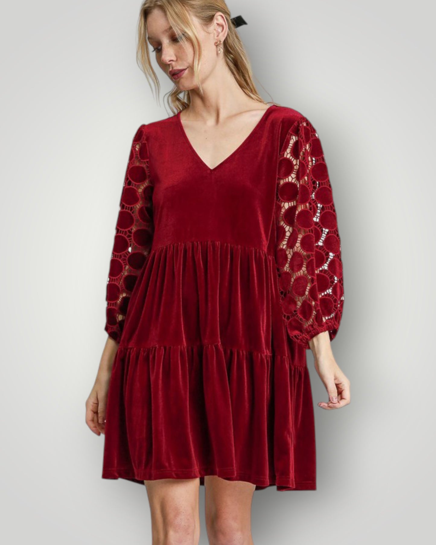 Woman wearing a red dress with patterned sleeves on a plain background