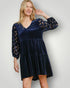 Woman wearing a navy velvet dress with leopard print sleeves against a plain background