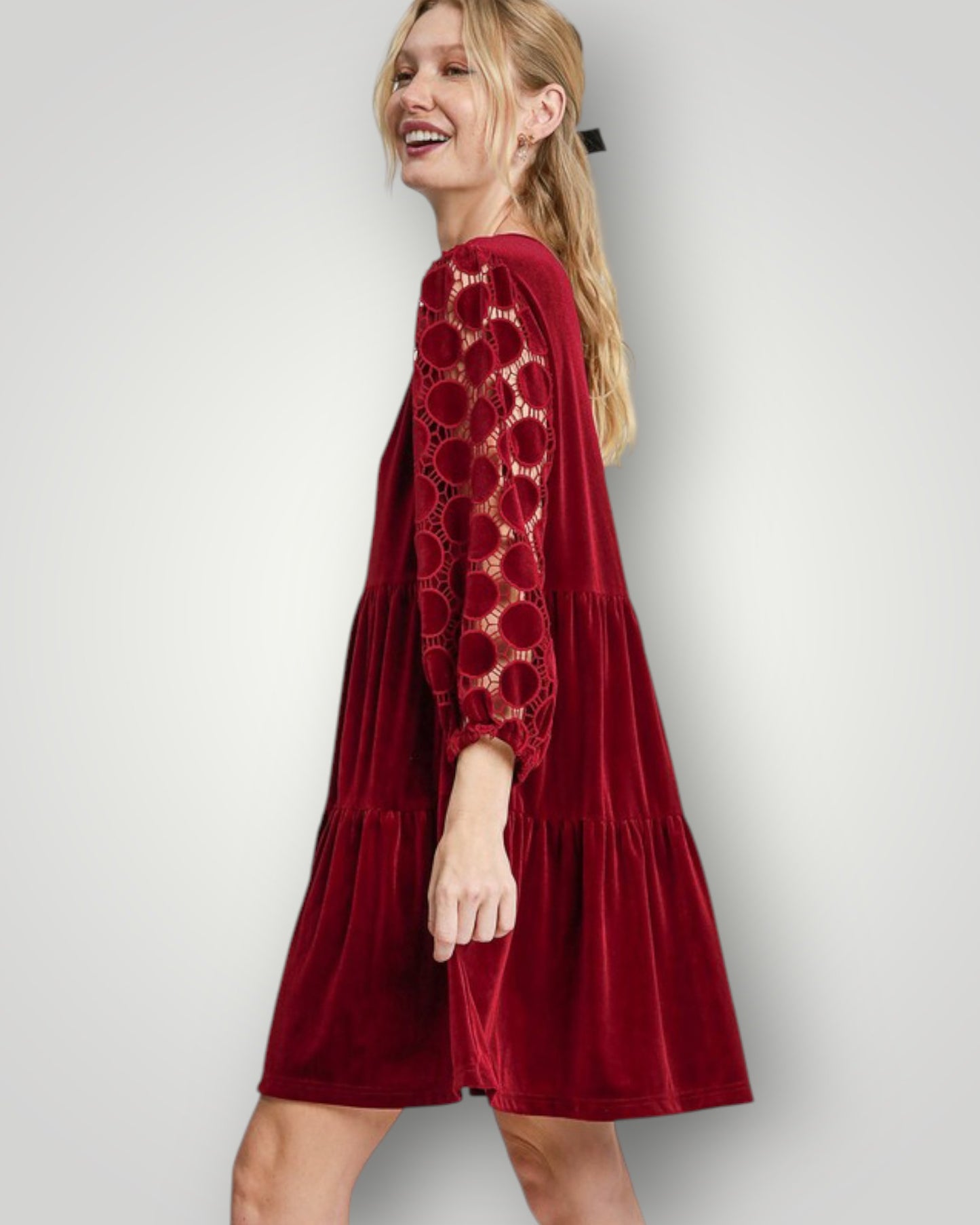 Woman wearing a red dress with lace details on a white background