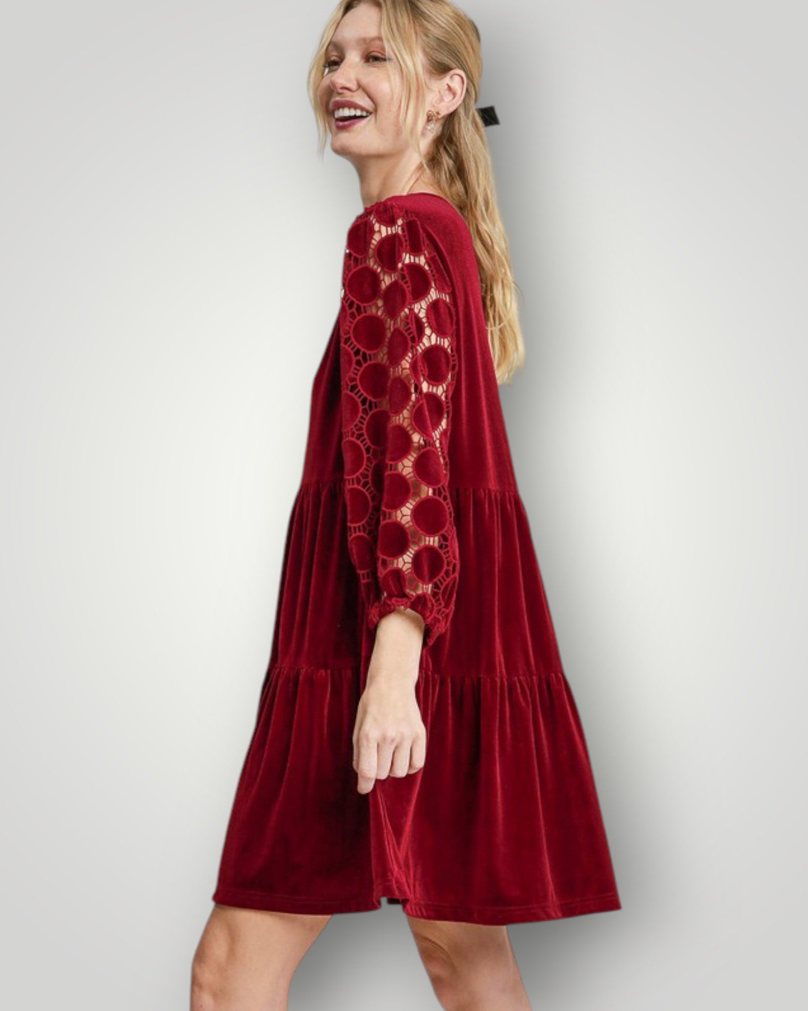 Woman wearing a red dress with lace details on a white background