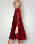Woman wearing a red dress with lace details on a white background