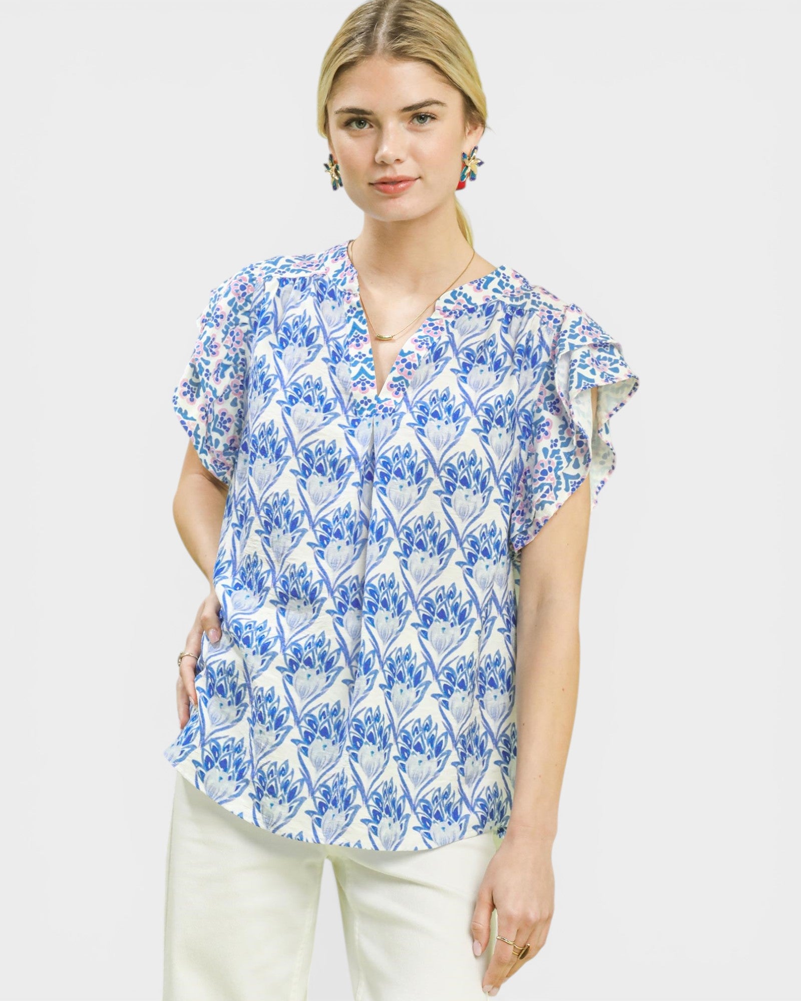 Woman wearing a blue and white patterned blouse on a plain background