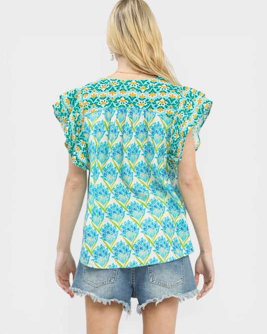 Woman wearing a floral patterned top and denim shorts on a white background