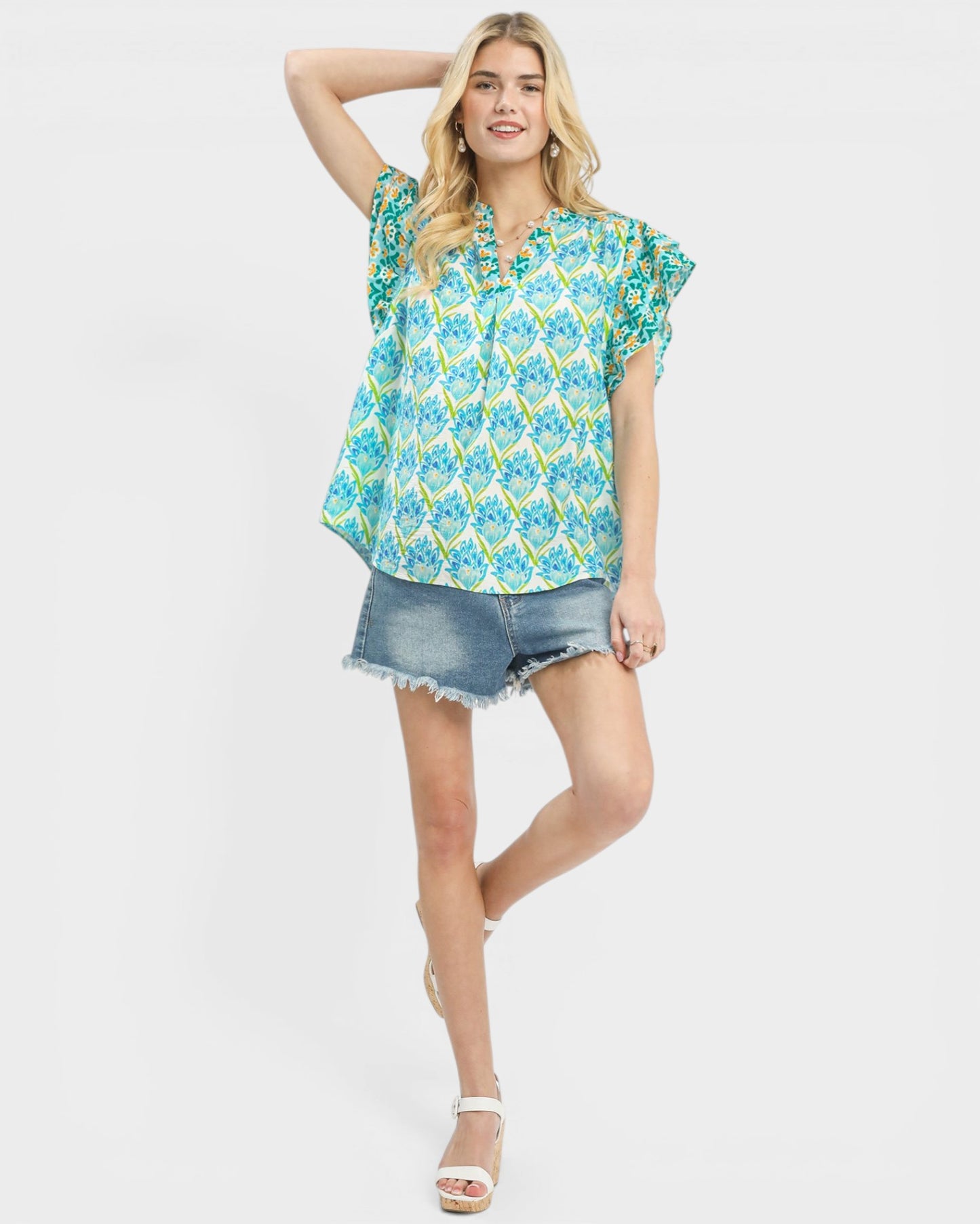 Woman wearing a floral blouse and denim shorts on a white background