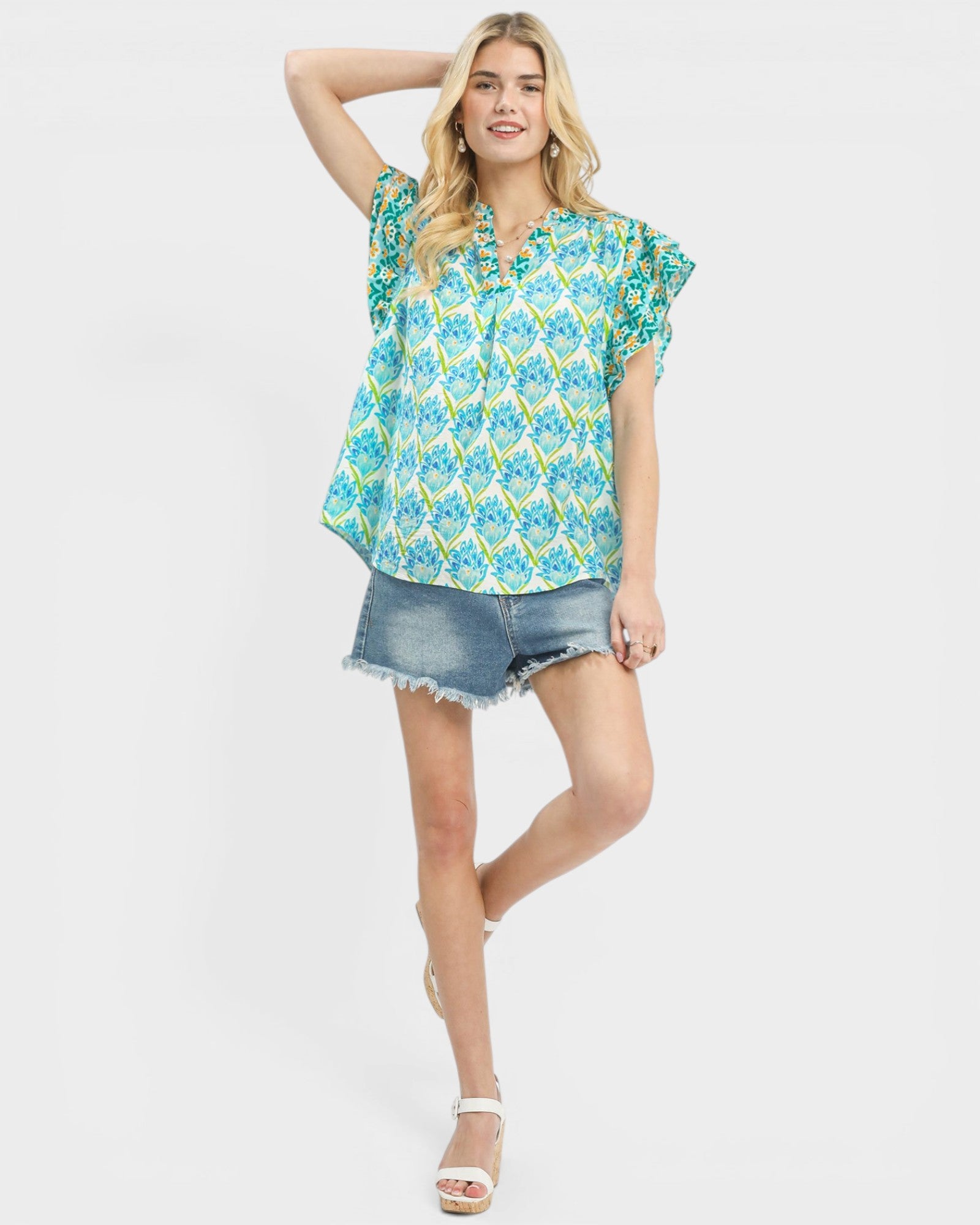 Woman wearing a floral blouse and denim shorts on a white background