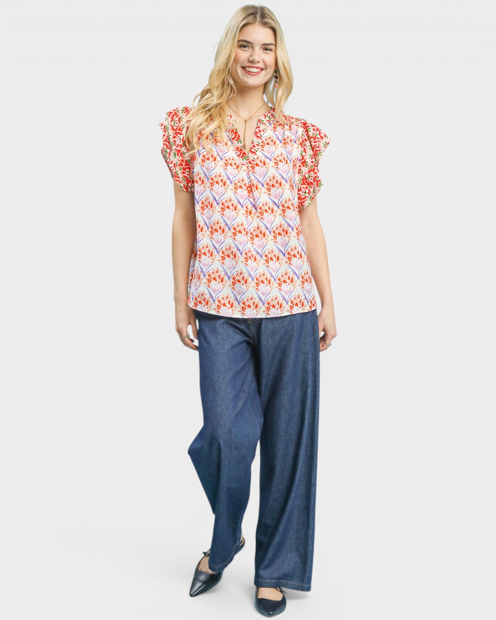 Woman wearing a floral top and blue pants on a white background