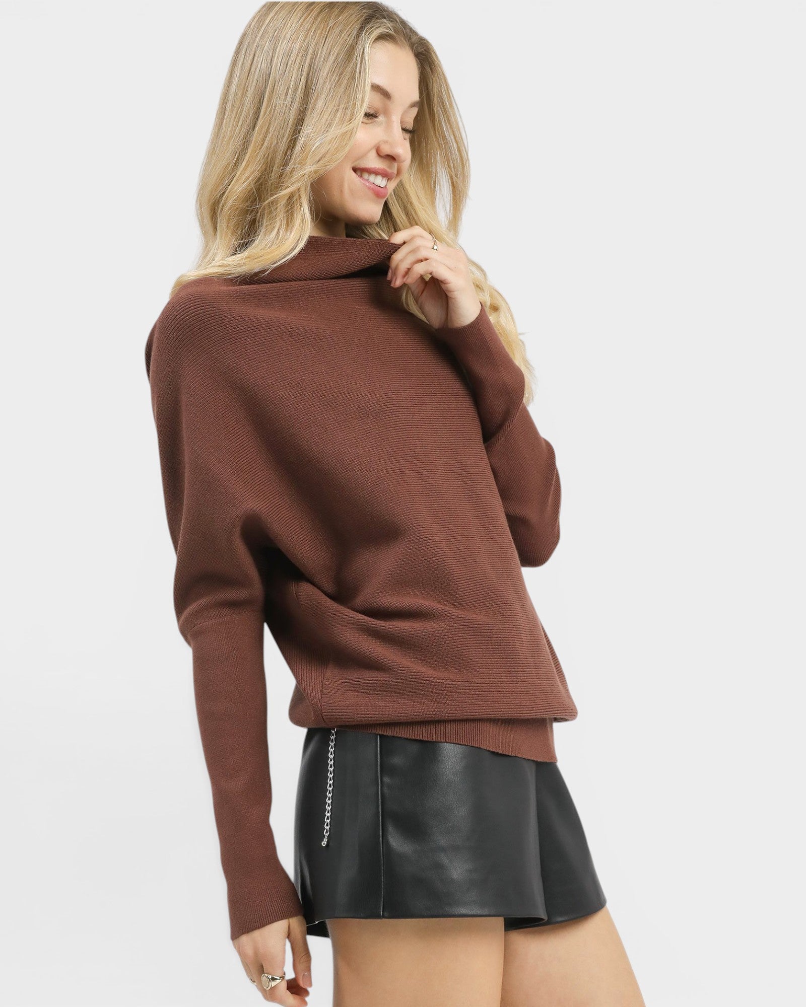 Woman wearing a brown sweater and black leather skirt on a white background