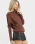 Woman wearing a brown sweater and black leather skirt on a white background