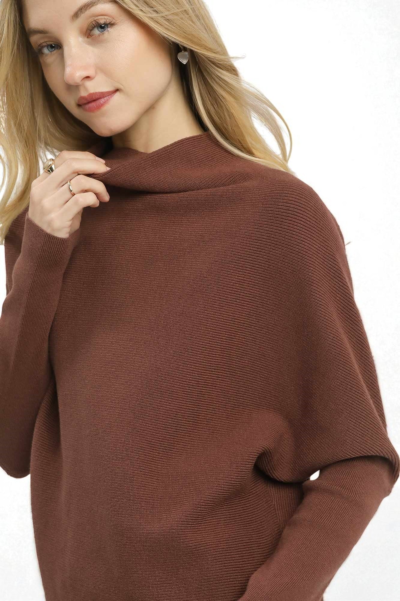 Woman wearing a brown poncho against a white background