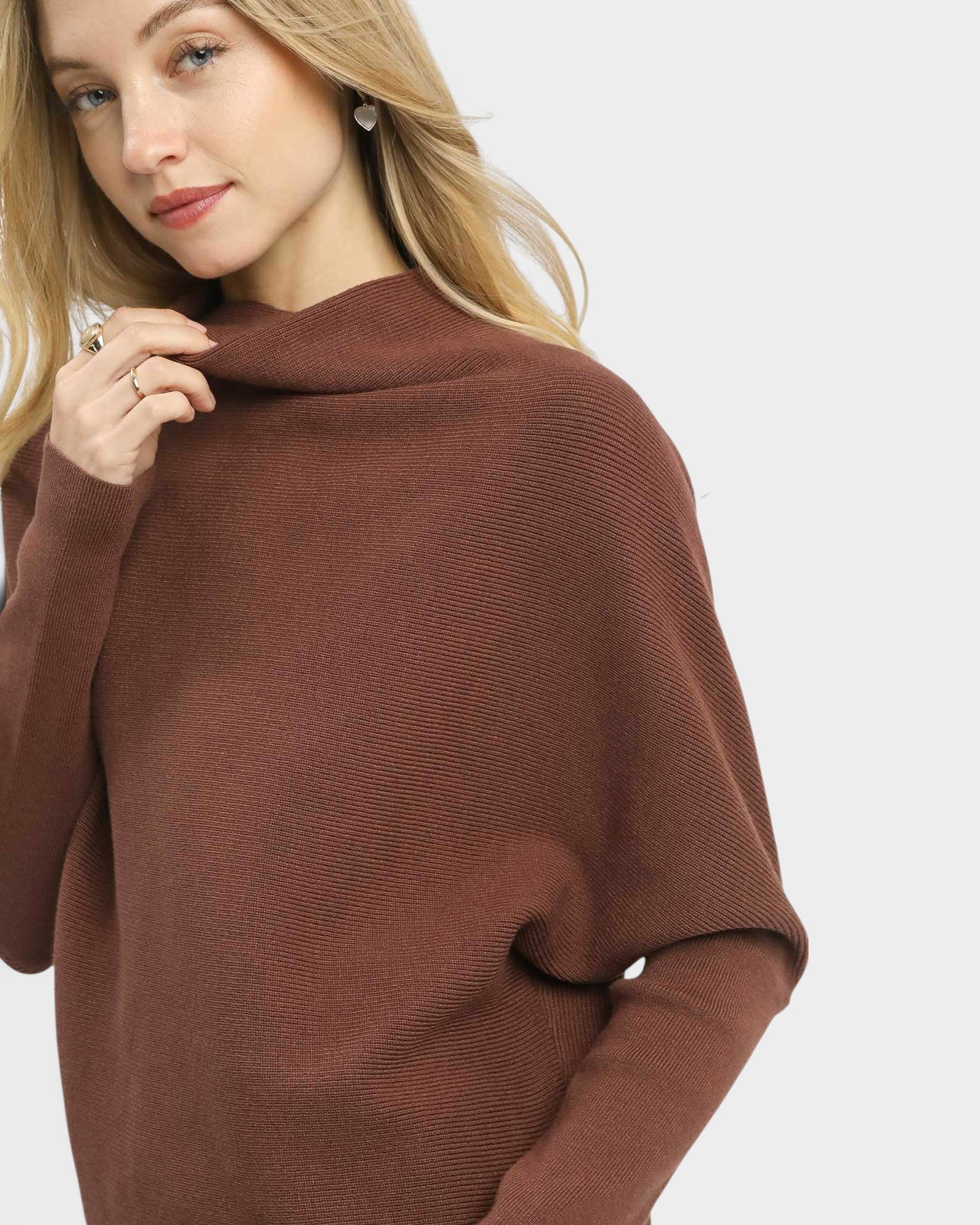Woman wearing a brown poncho against a white background