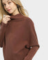 Woman wearing a brown poncho against a white background