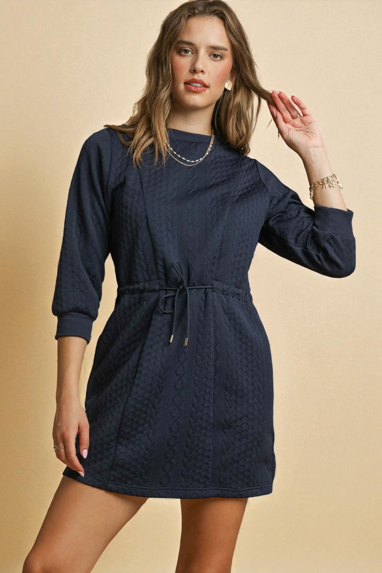Woman wearing a navy blue dress against a beige background