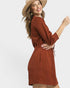 Woman wearing a rust-colored dress and beige hat on a white background