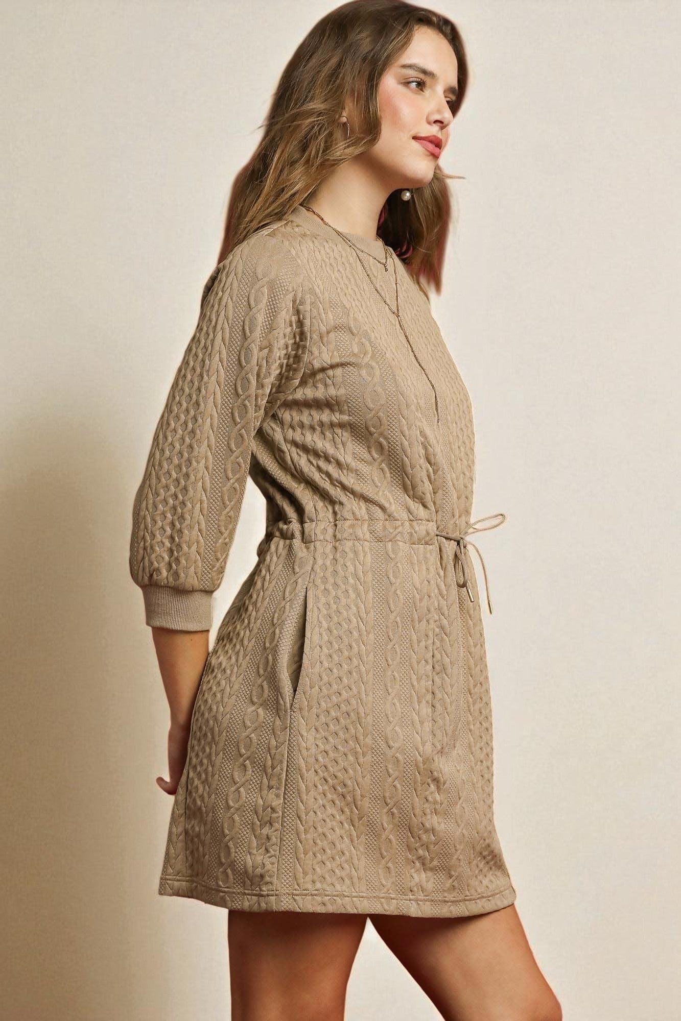 Woman wearing a beige patterned dress against a plain background