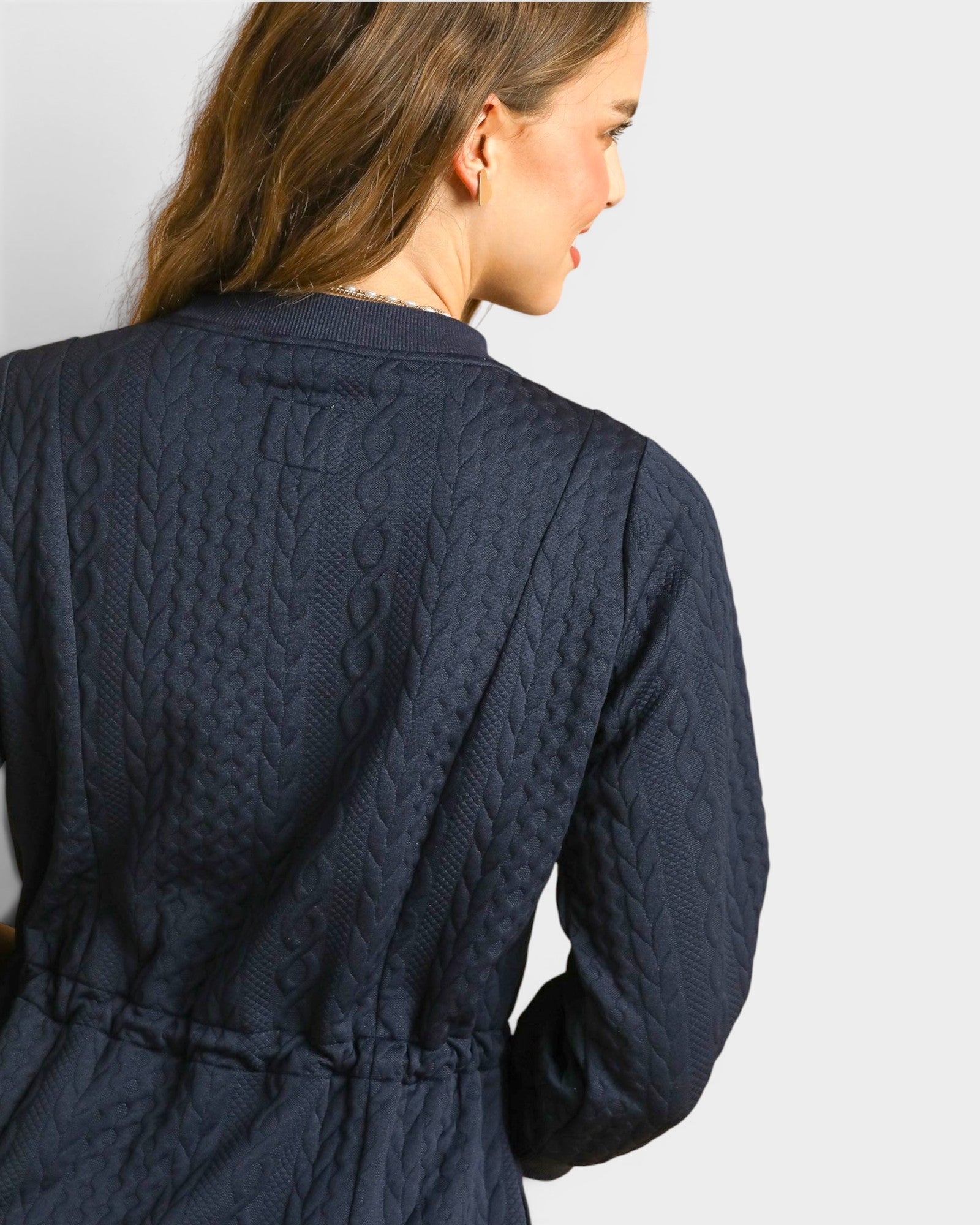 Woman wearing a navy quilted jacket on a plain background