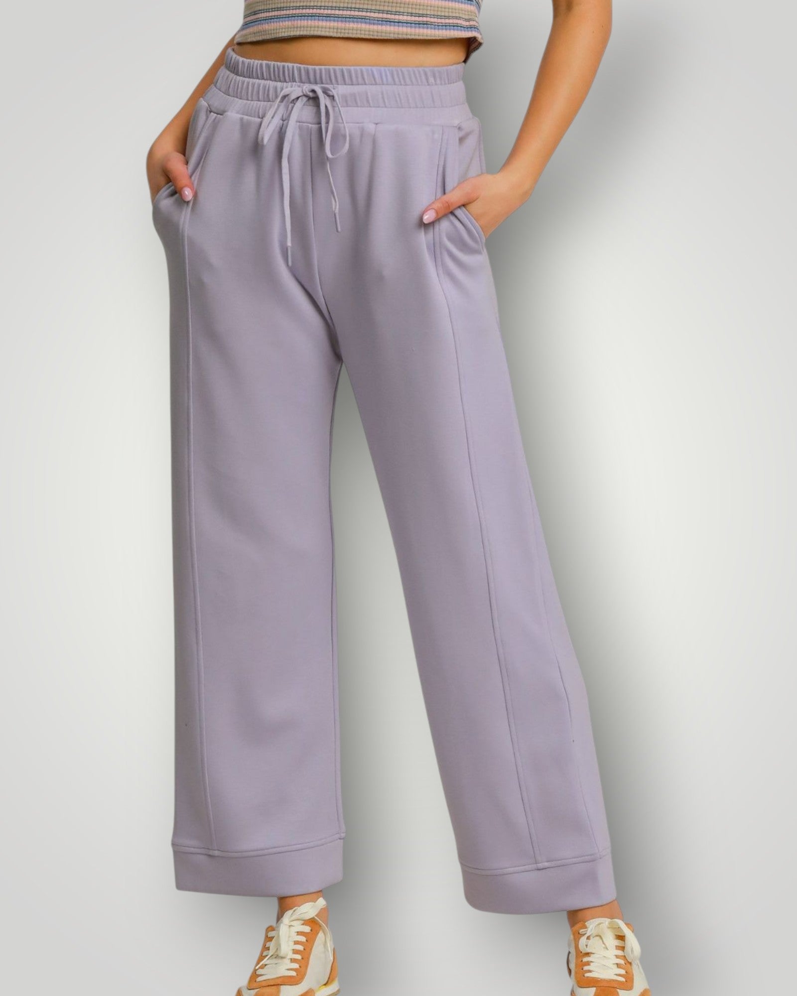 Person wearing lavender sweatpants on a plain background