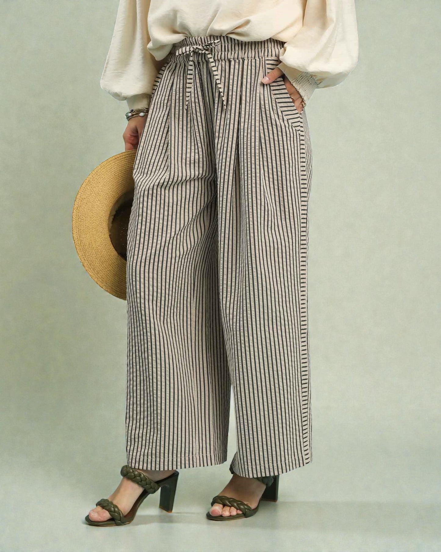 Person wearing striped wide-leg pants with a plain background