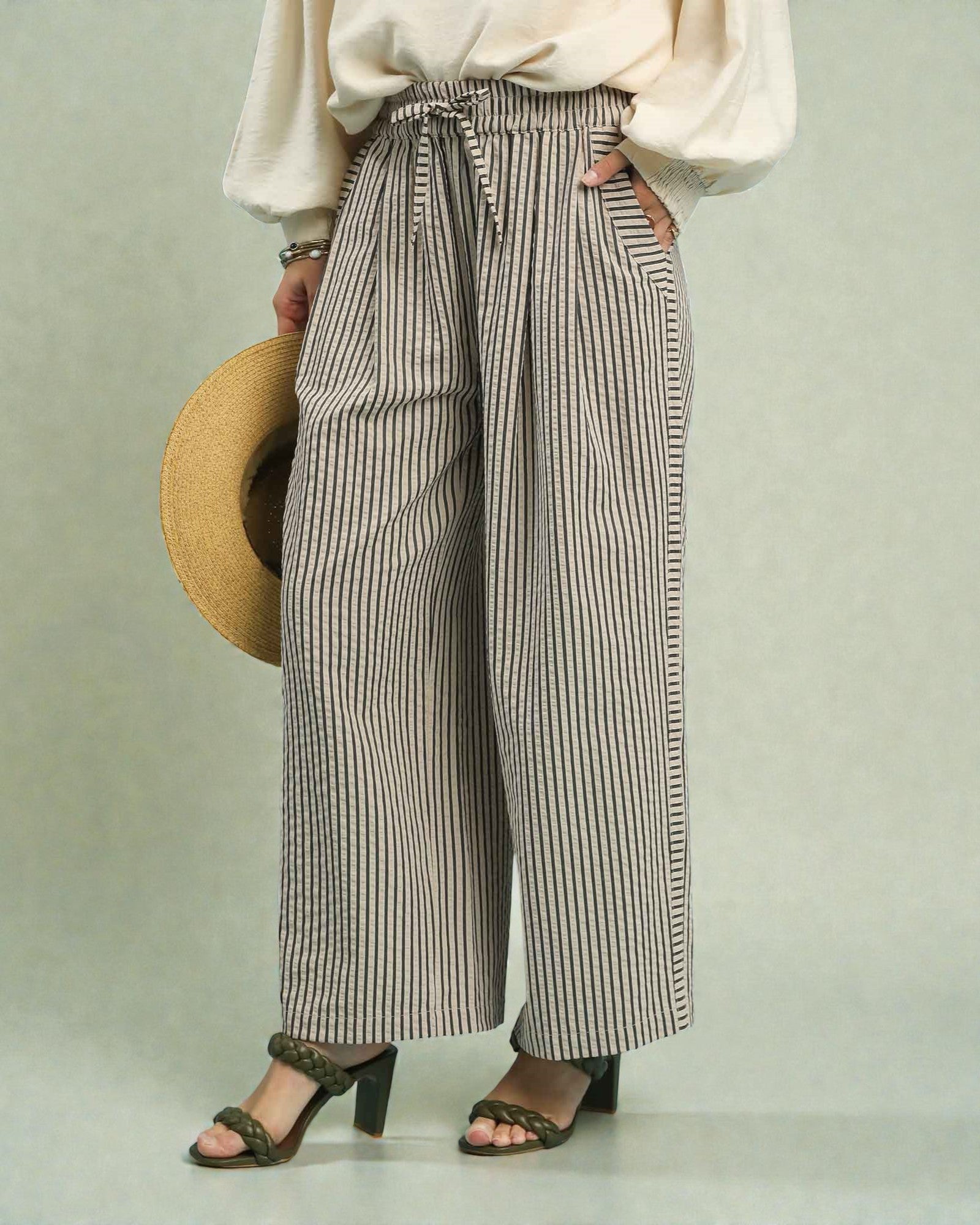 Person wearing striped wide-leg pants with a plain background