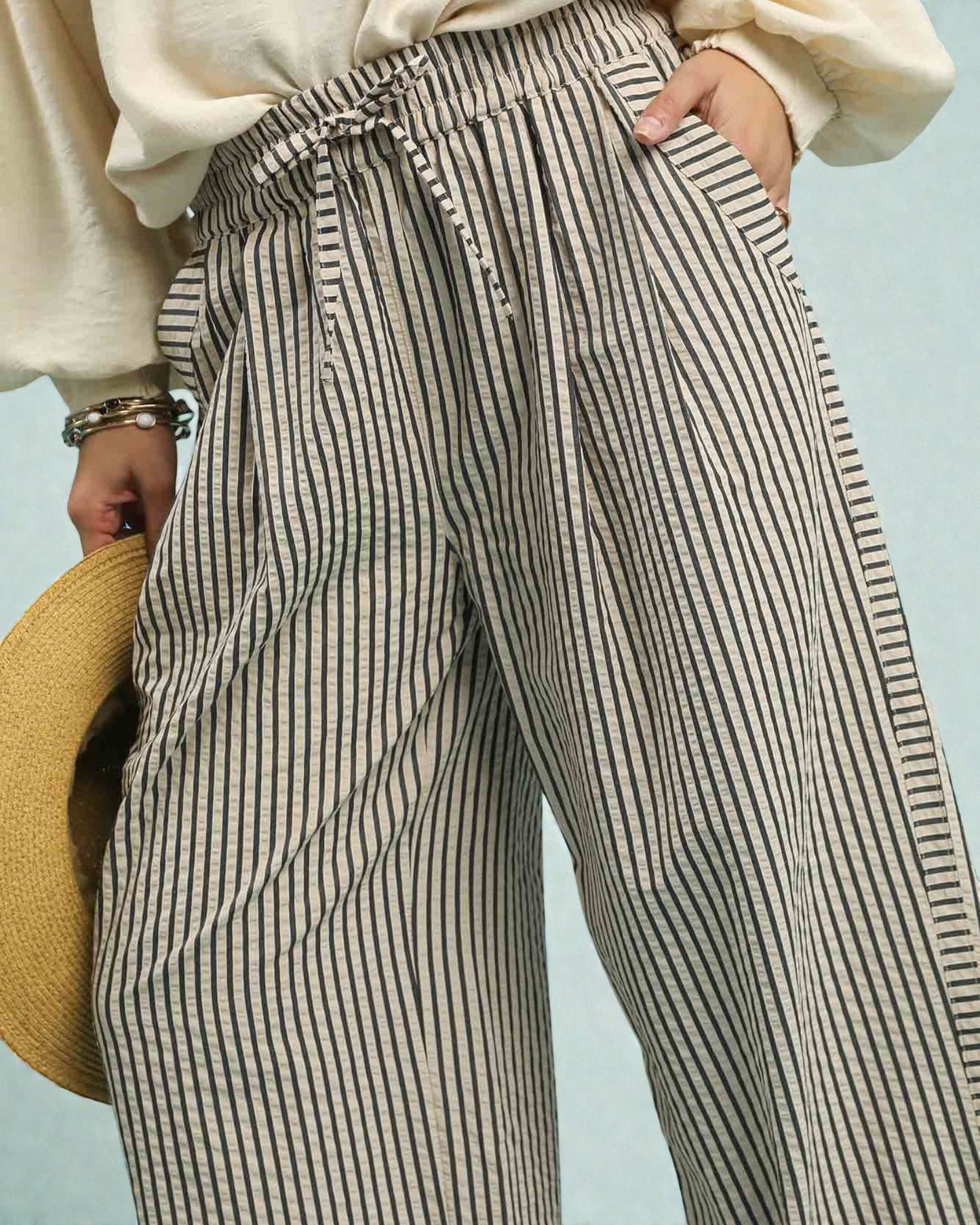 Person wearing black and white striped pants with a light blue background