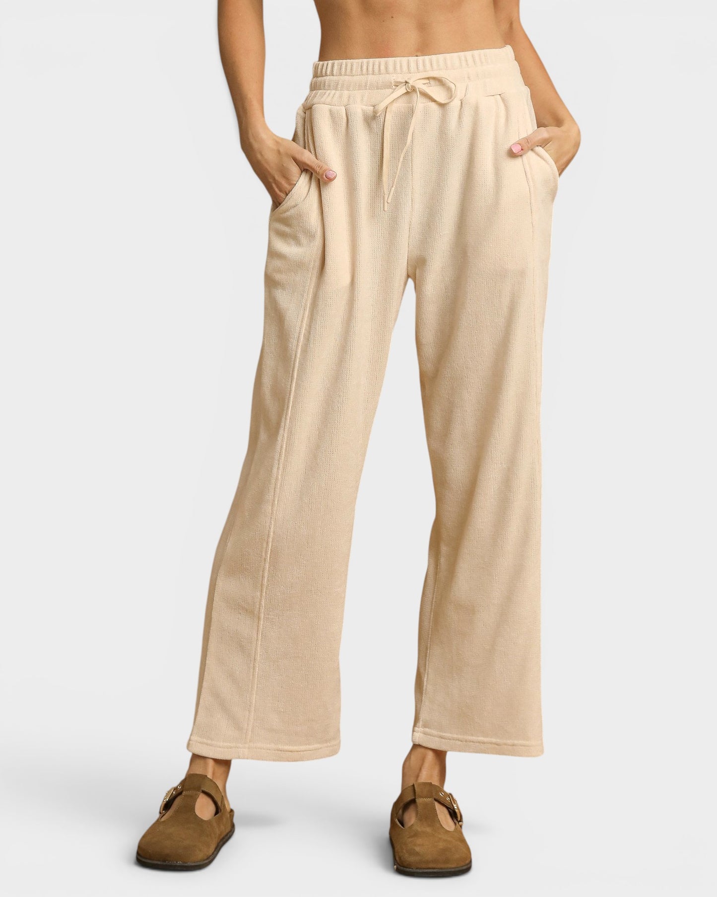 Beige lounge pants worn by a person on a white background