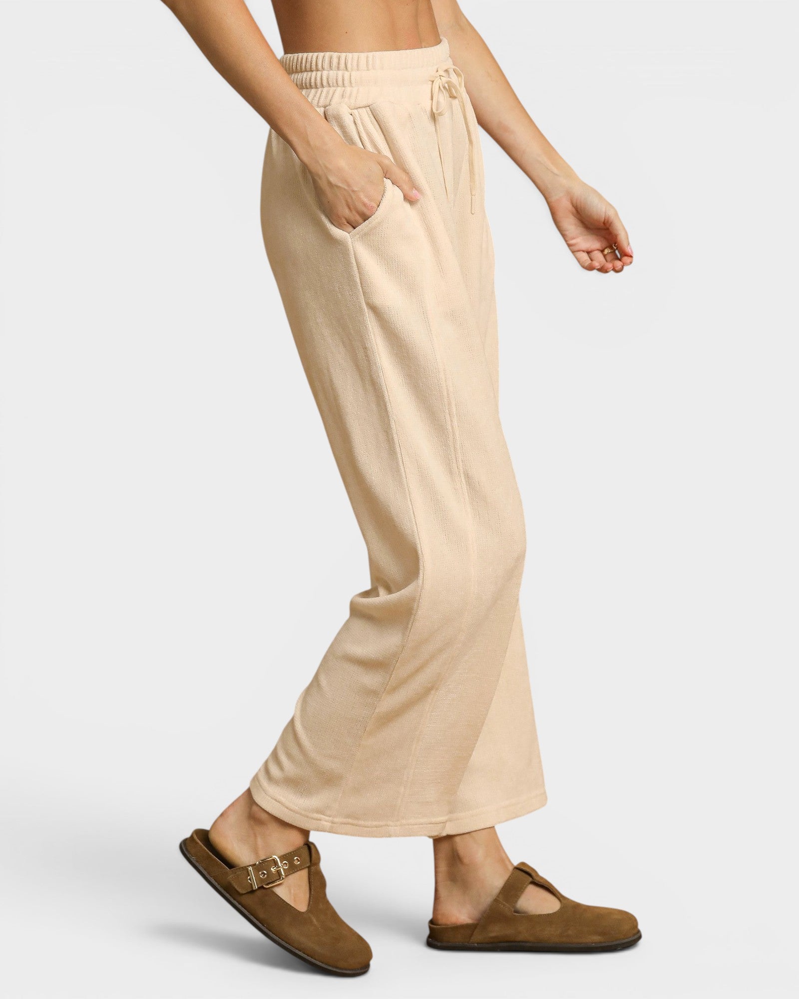 Beige lounge pants worn by a person on a white background