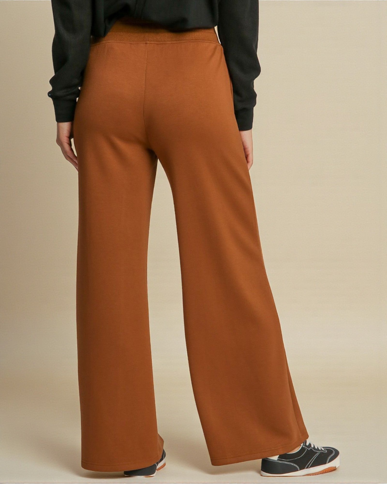 Brown wide-leg pants worn by a person on a beige background