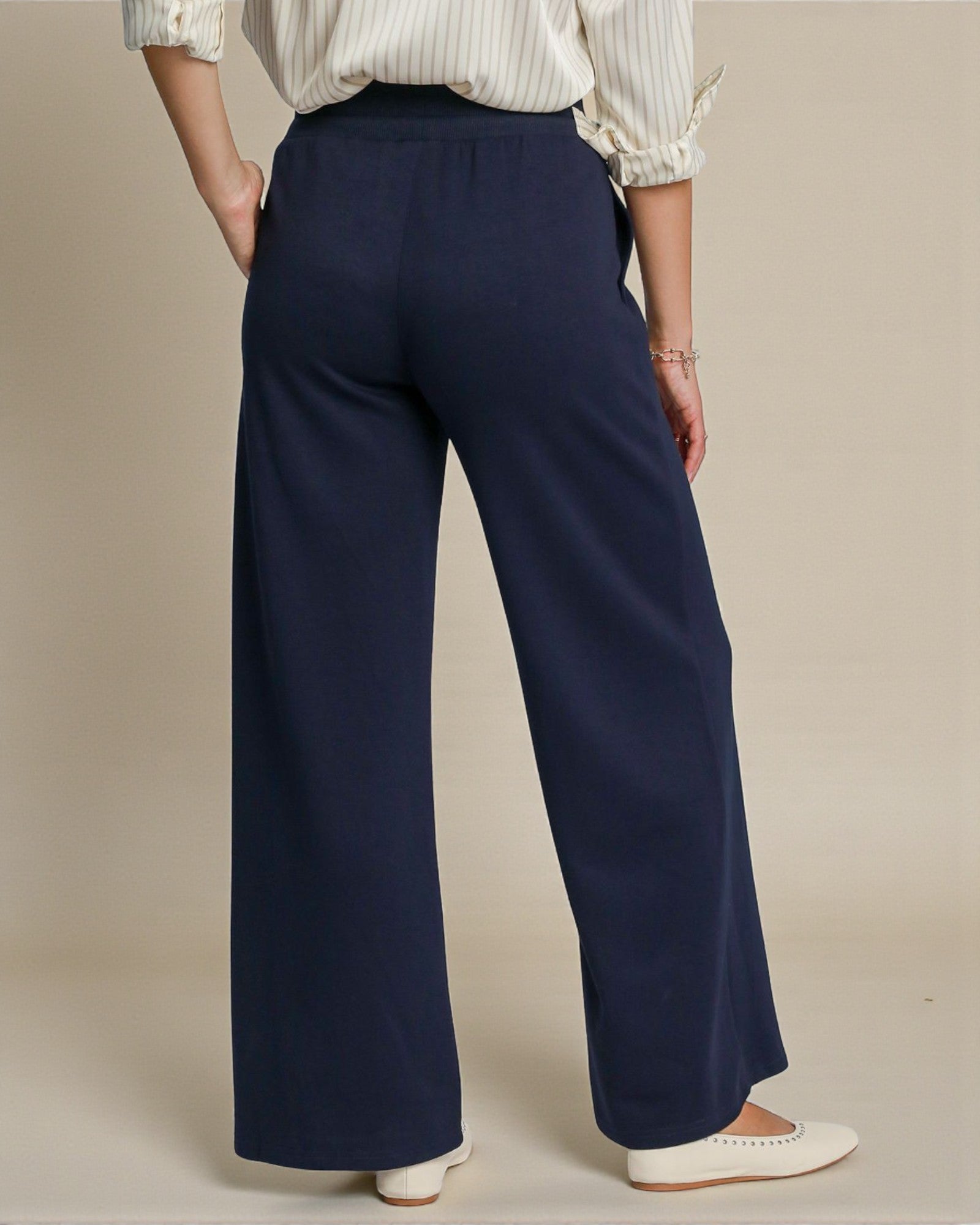 Navy wide-leg pants worn by a person on a beige background