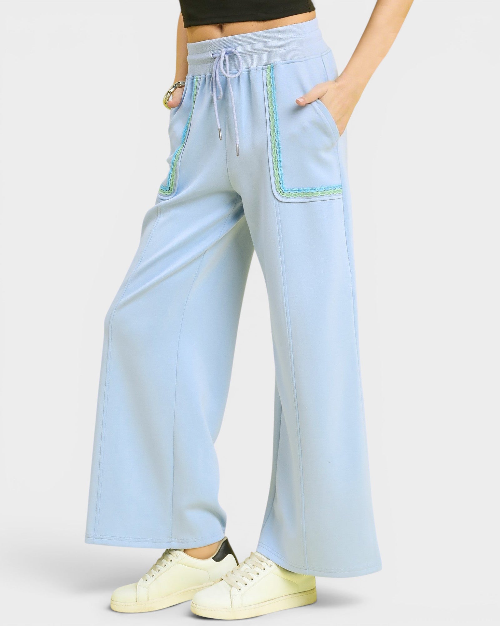 Light blue wide-leg pants with green accents worn by a person on a white background