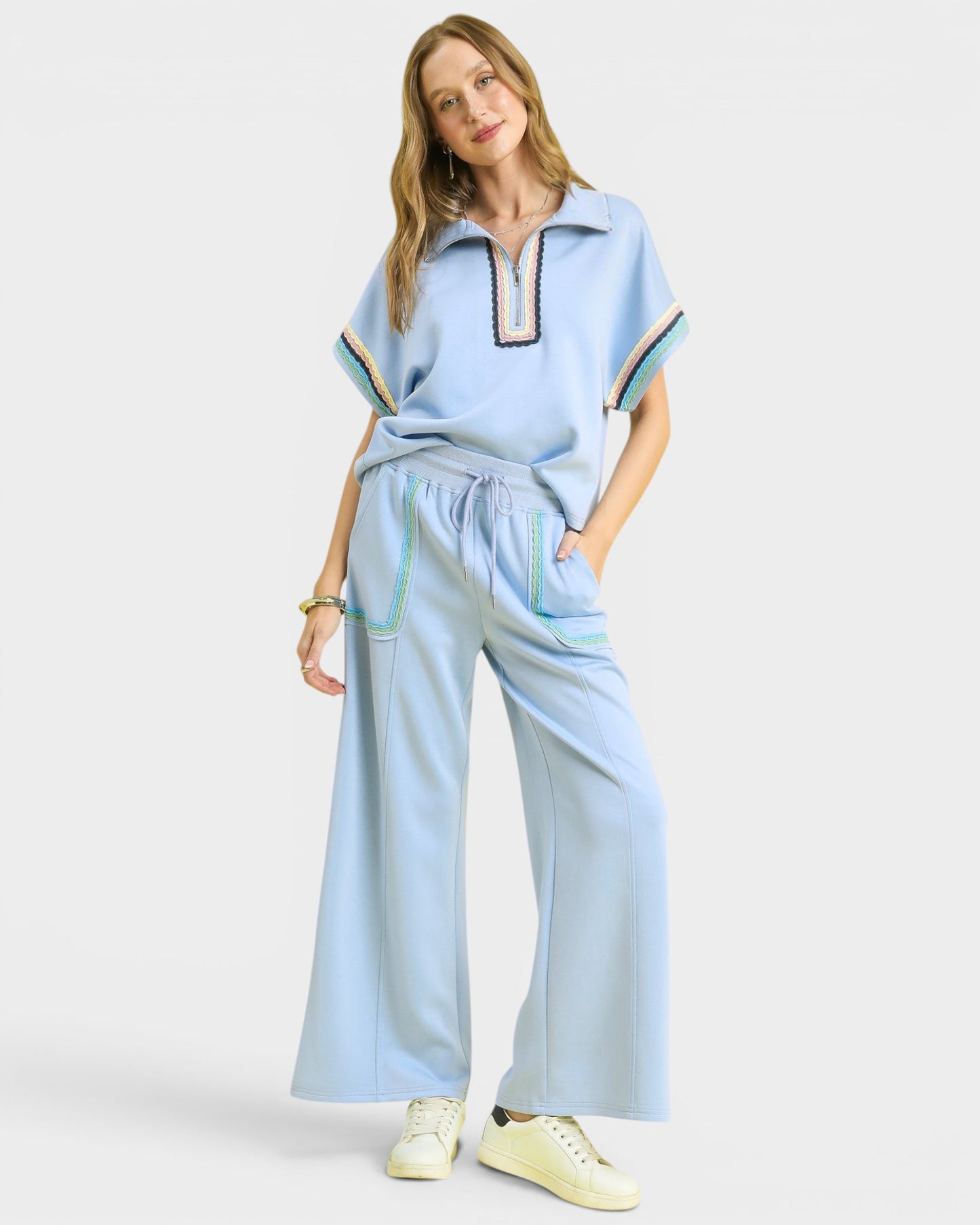Woman wearing a light blue outfit with a matching top and wide-leg pants on a white background