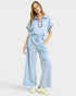 Woman wearing a light blue outfit with a matching top and wide-leg pants on a white background