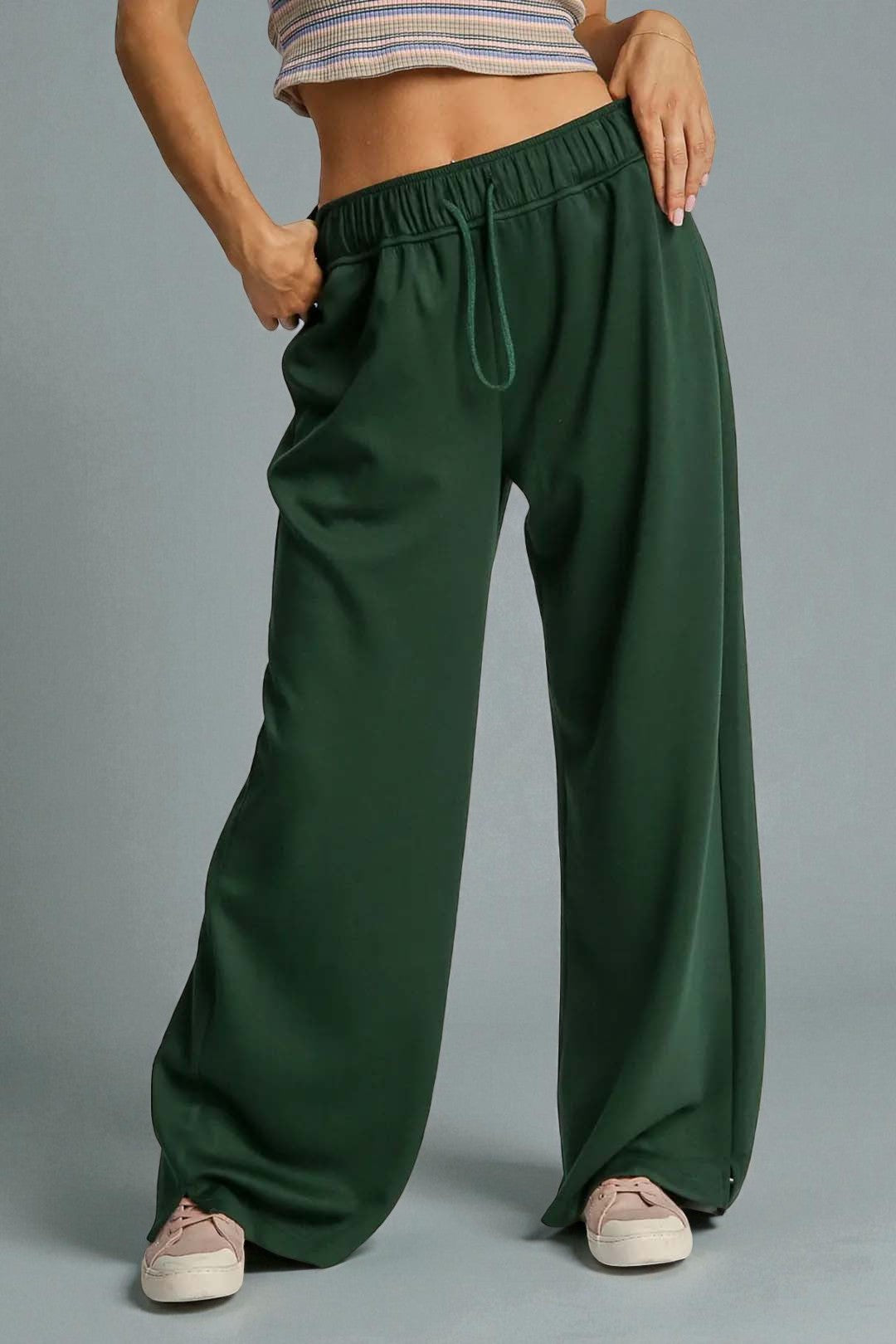 Green wide-leg pants worn by a person on a gray background