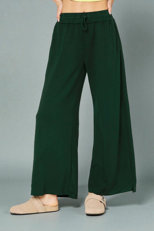 Green wide-leg pants worn by a person on a gray background