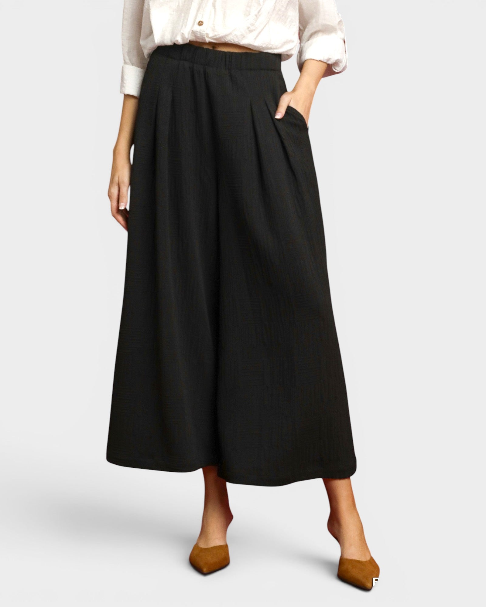 Person wearing a black skirt with a white shirt on a light gray background