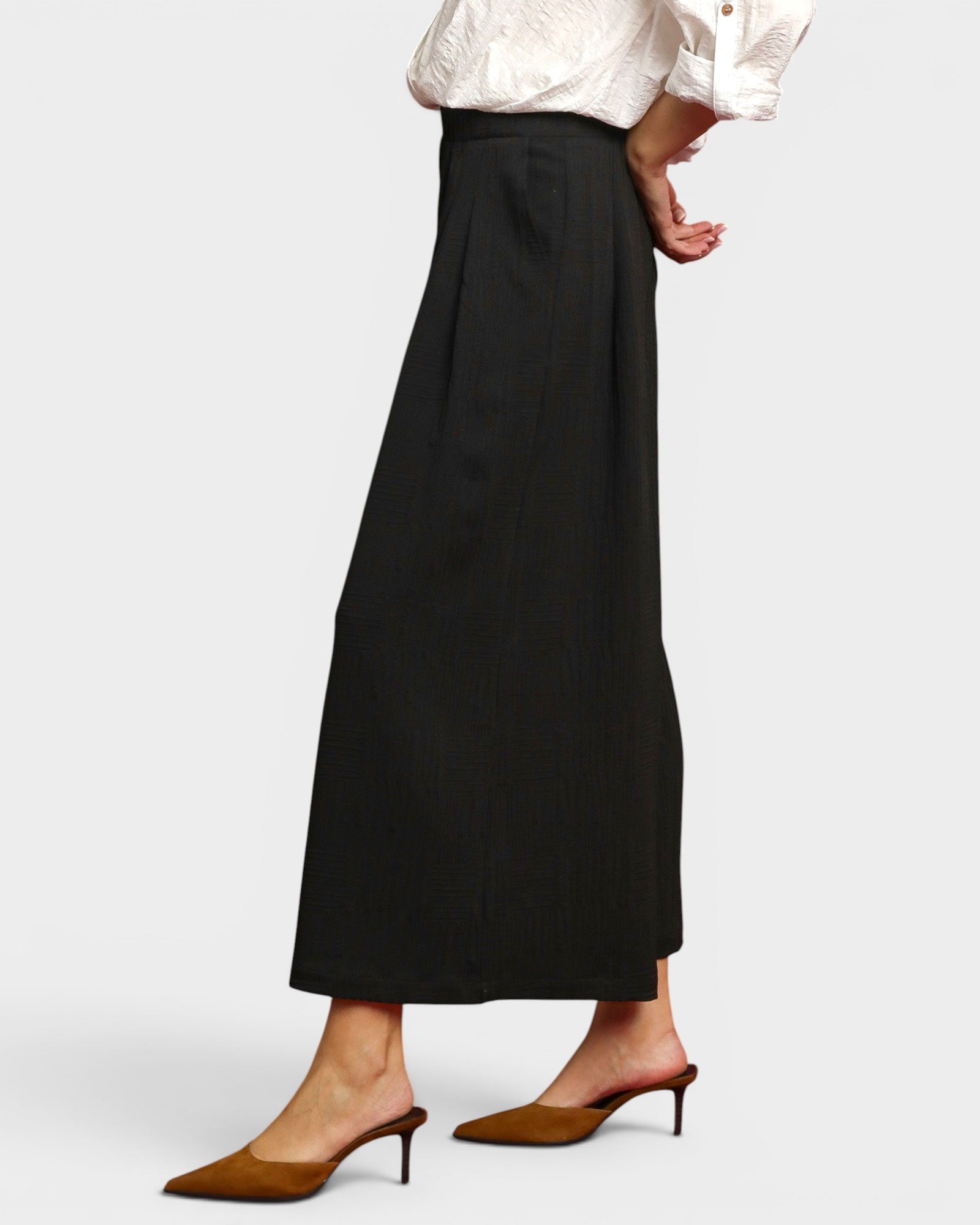 Person wearing a black wide-leg pants and white shirt on a light gray background