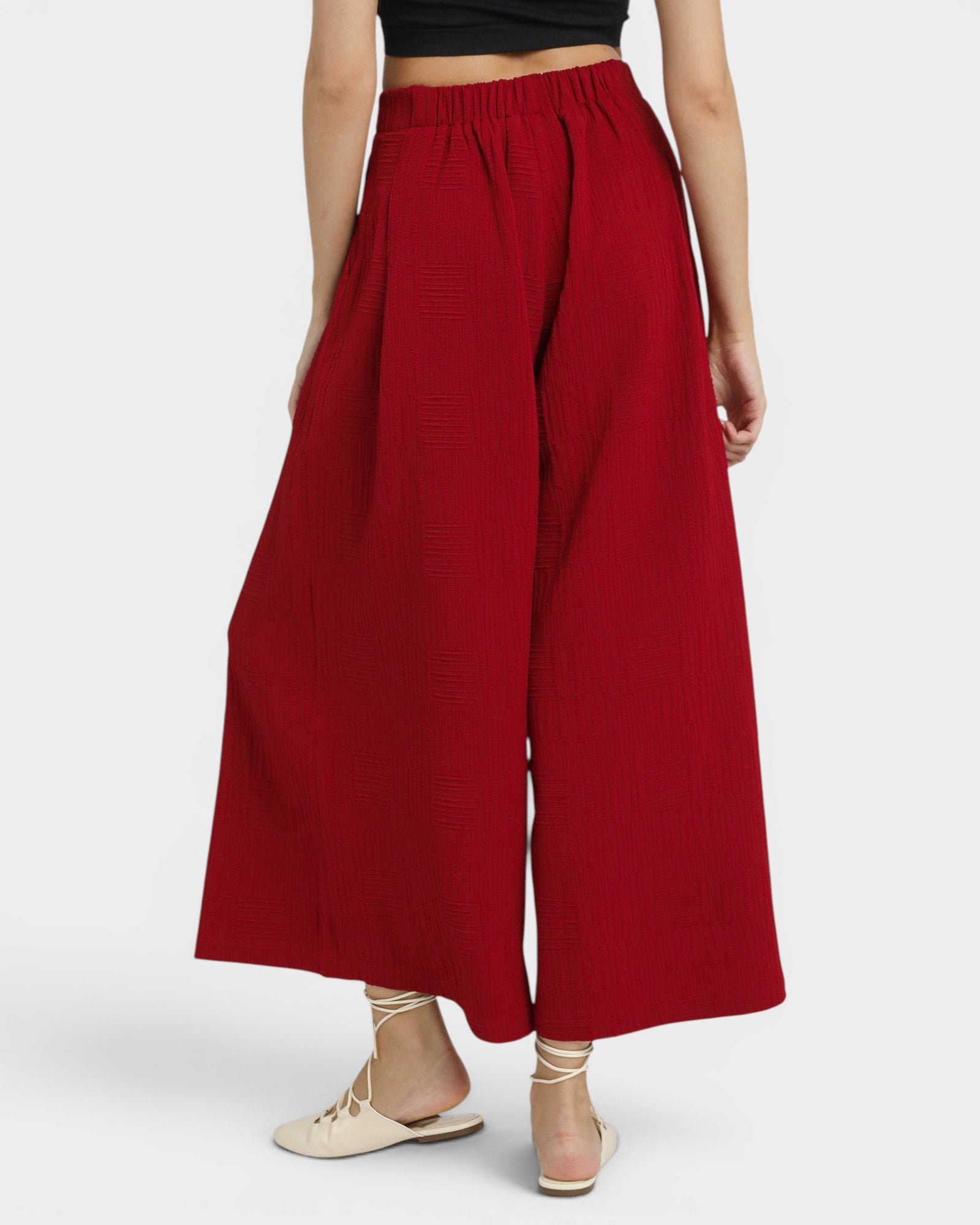 Red wide-leg pants worn by a person on a white background