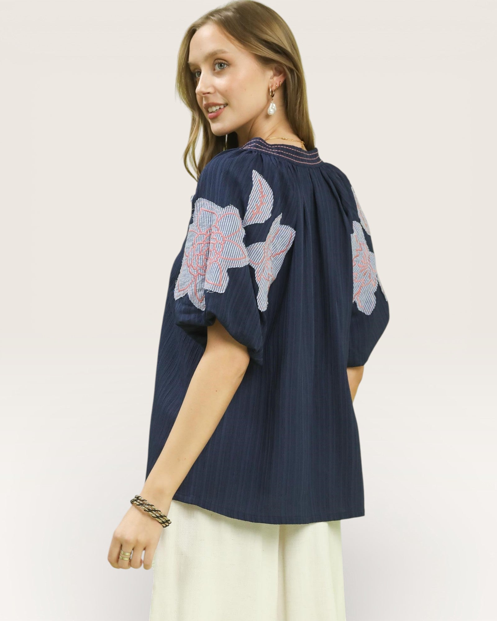 Woman wearing a navy blue blouse with floral patterns on a white background