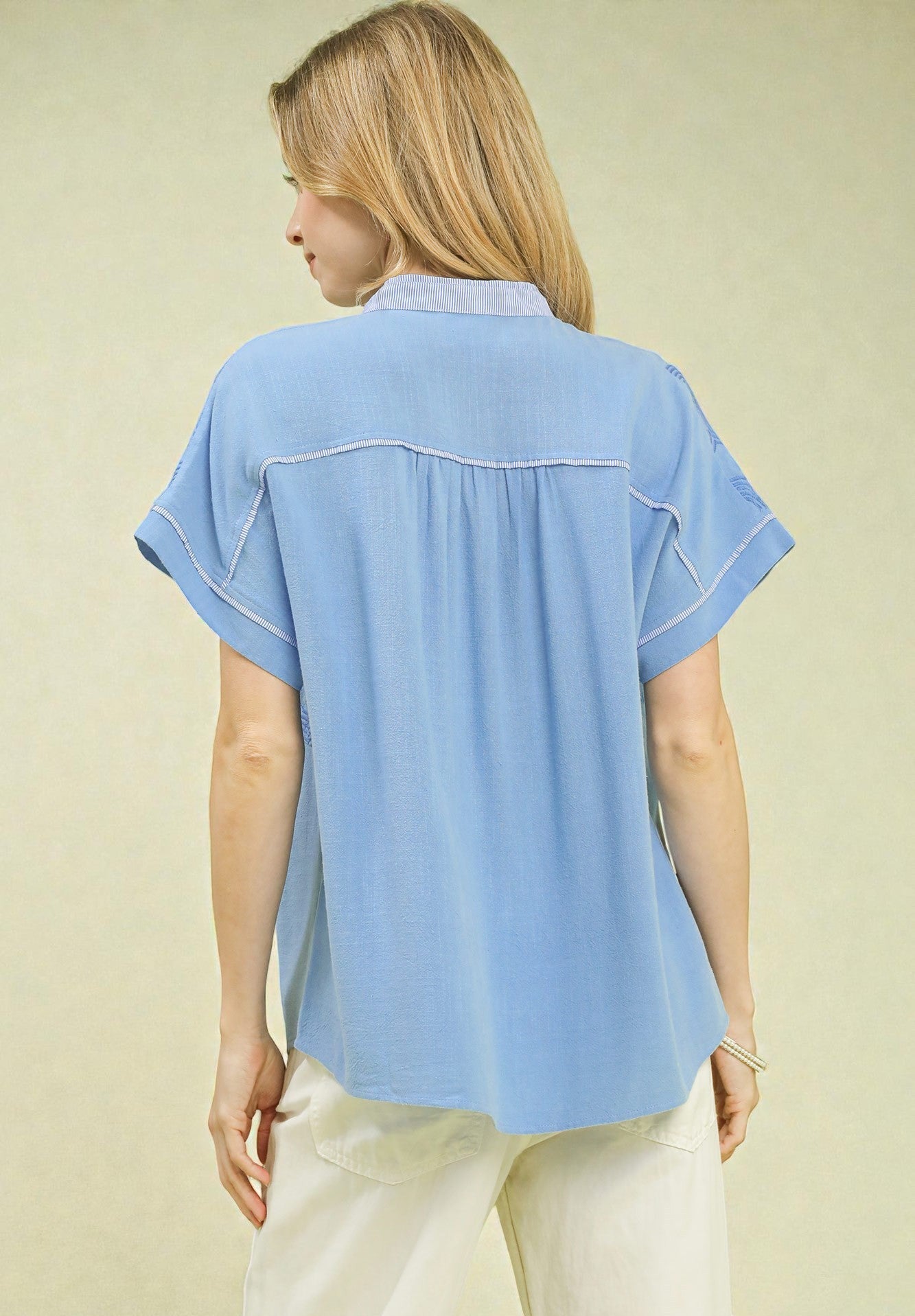 Woman wearing a light blue blouse with a plain background